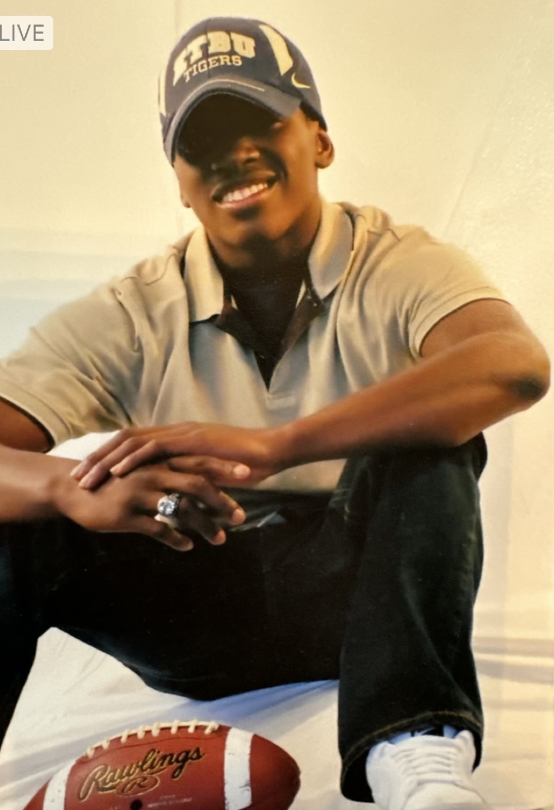 Cartez smiling in an LSU cap with a football