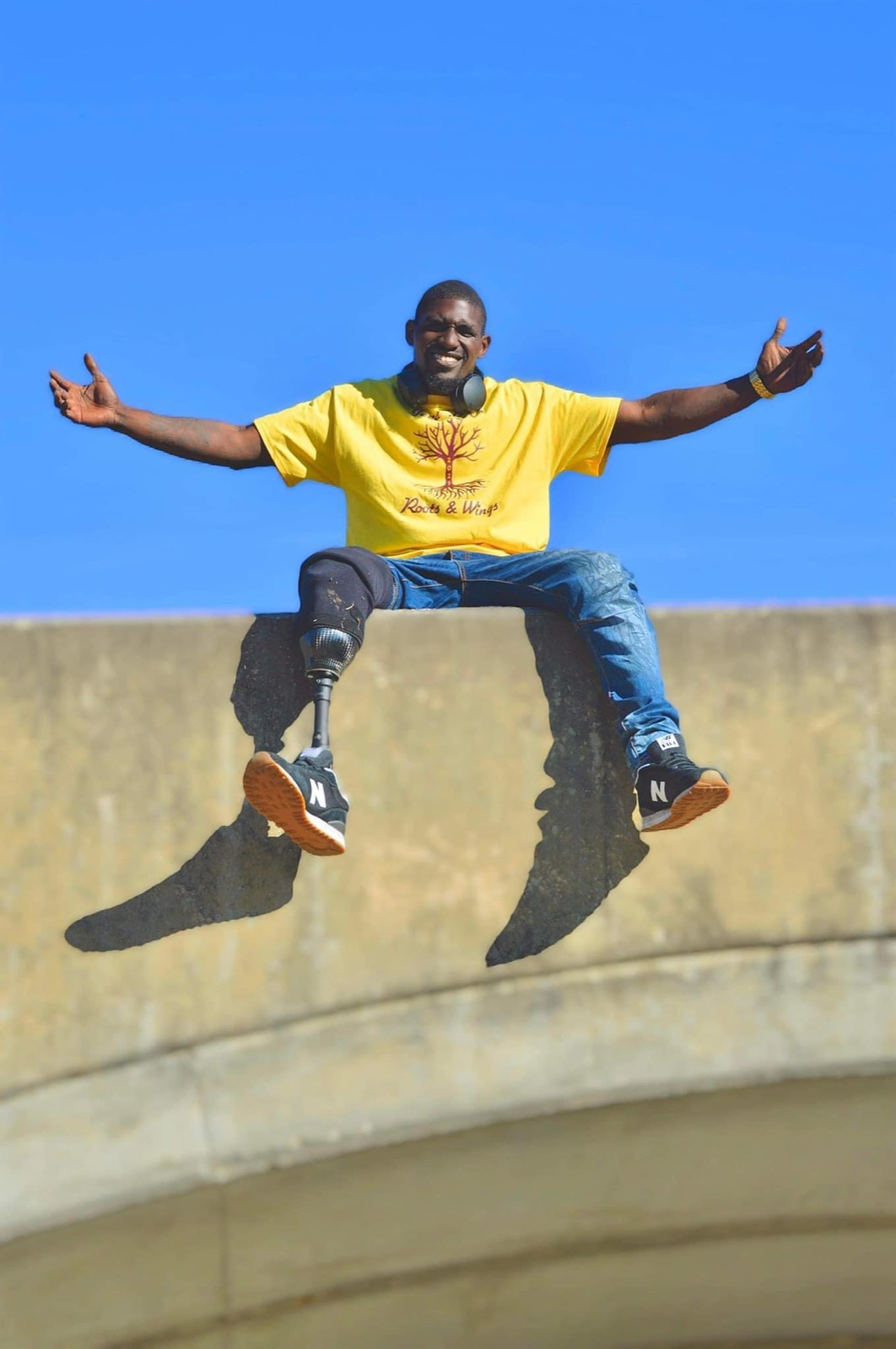 Cartez smiling with his arms open beneath a bright blue sky